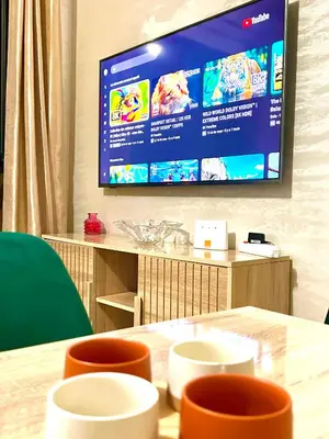 a television hanging on a wall with a table and chairs at Appartement Denda in Marrakech