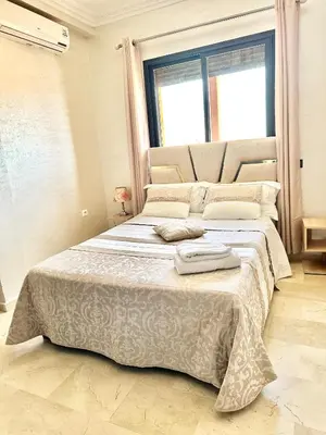 a large bed in a room with a large window at Appartement Denda in Marrakech