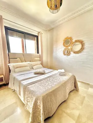 a bedroom with a large bed with two mirrors on the wall at Appartement Denda in Marrakech