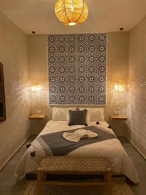 a bedroom with a bed with a bench and two lights at Riad212 private medina fast Wi-Fi plunge pool in Marrakech
