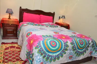 a bed with a colorful comforter and pink pillows at Cheap accommodation in Marrakech in Marrakech