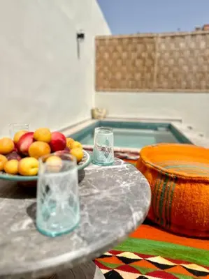 a table with a bowl of fruit and glasses at Maison de ville avec piscine in Marrakech