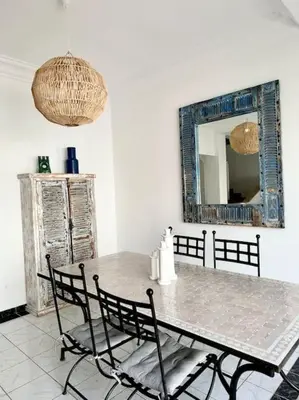 a table and chairs in a room with a mirror at Maison de ville avec piscine in Marrakech