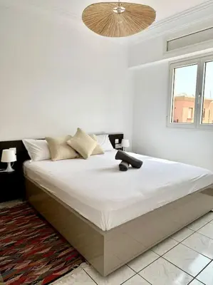 a white bedroom with a large bed with a ceiling at Maison de ville avec piscine in Marrakech