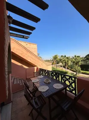 a patio with a table and chairs on a balcony at Cozy apartment with roof top in Marrakech