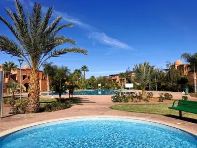 a pool with a palm tree and a bench at Cozy apartment with roof top in Marrakech
