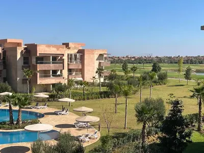 a resort with a pool and chairs and umbrellas at New appart, pool and golf view in Marrakech
