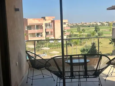 a balcony with a table and chairs and a view at New appart, pool and golf view in Marrakech