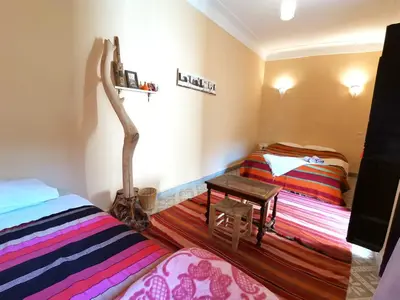 a bedroom with two beds and a table in it at Dar Mirai in Marrakech