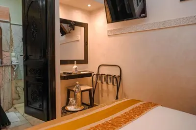 a bedroom with a bed and a mirror and a chair at Riad Roummana Marrakech in Marrakech