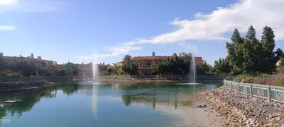 a pond with a fountain in front of a building at Les Jardins de la palmeraie in Marrakech