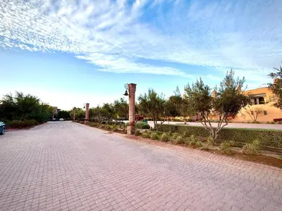 a brick road with a clock tower in a park at Les Jardins de la palmeraie in Marrakech