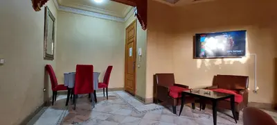 a room with a table and chairs and a tv on the wall at Les Jardins de la palmeraie in Marrakech