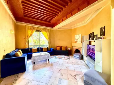 a living room with blue couches and a tv at Les Jardins de la palmeraie in Marrakech