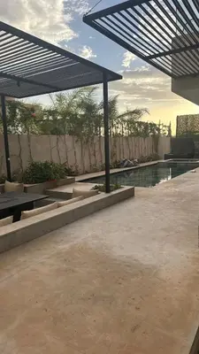 a patio with a swimming pool and a large umbrella at magnifique villa golf amelkis sans vis-à-vis in Marrakech