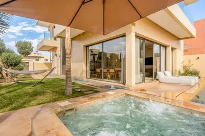 a swimming pool with an umbrella in front of a house at Villa Tolède by TheCasaEdition in Marrakech
