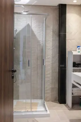 a shower with a glass door in a bathroom at Appartement Uniquement Familial 2 Chambres spacieux cosy, calme in Marrakech