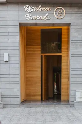 a wooden door of a building with a sign on it at Appartement Uniquement Familial 2 Chambres spacieux cosy, calme in Marrakech