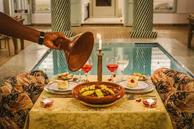 a person pouring wine into a table with a bowl of food at Riad Assouel et Spa By La Siredrah in Marrakech