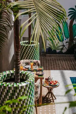 a patio with a table and a palm tree at Riad Assouel et Spa By La Siredrah in Marrakech