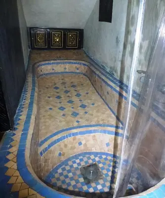 a bathroom with a tub with a tiled floor at Ryad Laârouss in Marrakech