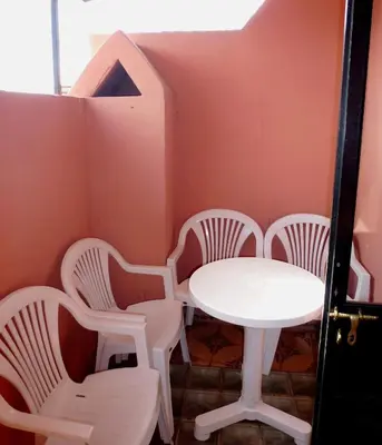 a table and chairs in a room with pink walls at Ryad Laârouss in Marrakech