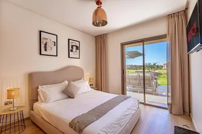 a bedroom with a bed and a sliding glass door at luxueux & spacieux appartement a prestigia in Marrakech