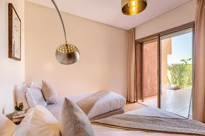 a bedroom with two beds and a sliding glass door at luxueux & spacieux appartement a prestigia in Marrakech