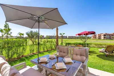 a patio table with an umbrella and a couch and chairs at luxueux & spacieux appartement a prestigia in Marrakech