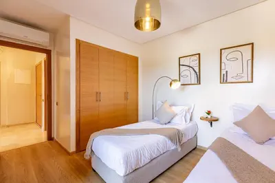 a bedroom with two beds and a closet at luxueux & spacieux appartement a prestigia in Marrakech