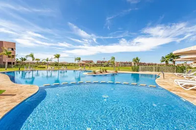 a large swimming pool in a resort with palm trees at luxueux & spacieux appartement a prestigia in Marrakech