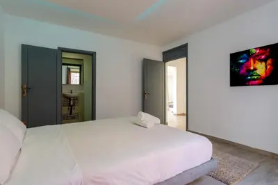 a bedroom with a white bed and a painting on the wall at Villa privée avec piscine Sans vis-à-vis, calme absolu in Marrakech