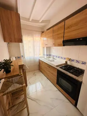 a kitchen with wooden cabinets and a stove top oven at Charmant appartement avec piscine 2chambres au cœur de Guéliz in Marrakech
