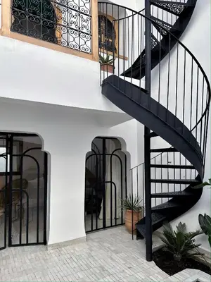 a black staircase in a white building with plants at Riad de l'Ô with Pool, Rooftop, Free Breakfast in Marrakech
