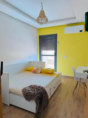 a bedroom with a bed with yellow walls at Jardin Yves Appartement 2 Chambres Chic in Marrakech