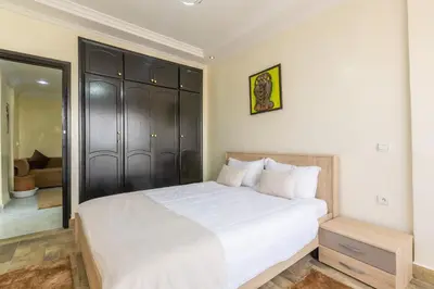 a bedroom with a white bed and a mirror at Appartement Raffiné au Centre in Marrakech