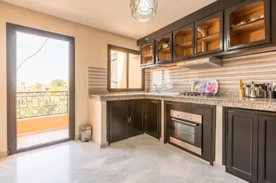 a kitchen with black cabinets and a large window at Appartement Raffiné au Centre in Marrakech