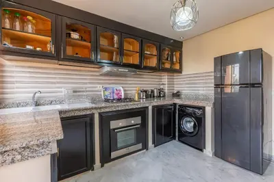 a kitchen with black cabinets and a washer and dryer at Appartement Raffiné au Centre in Marrakech