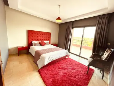 a bedroom with a bed with a red headboard and a red rug at Villa Dar El Hna in Marrakech