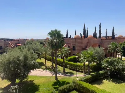 a courtyard of a building with palm trees and bushes at Strasmarrakech in Marrakech