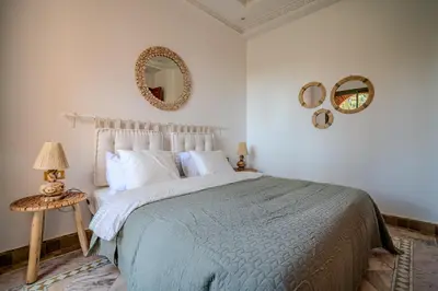 a bedroom with a bed and two mirrors on the wall at Family Stay aux jardins de la palmeraie in Marrakech