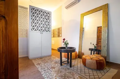 a hallway with a mirror and a table and a stool at Riad Dekkak, Maison complète en exclusivité in Marrakech