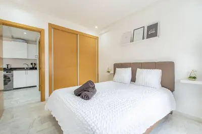a bedroom with a white bed and a kitchen at New! Guéliz , Modern , Terrasse in Marrakech