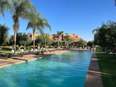 a swimming pool in a park with palm trees at Appartement avec Solarium Privé au Vizir Résidence Prestigieuse avec Accès au Parc in Marrakech
