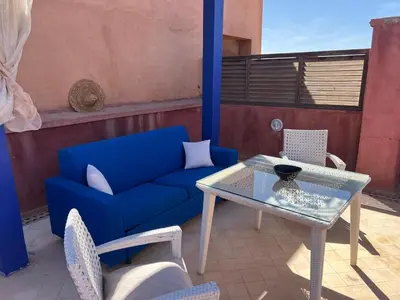 a blue couch and a table and chairs on a patio at Appartement avec Solarium Privé au Vizir Résidence Prestigieuse avec Accès au Parc in Marrakech