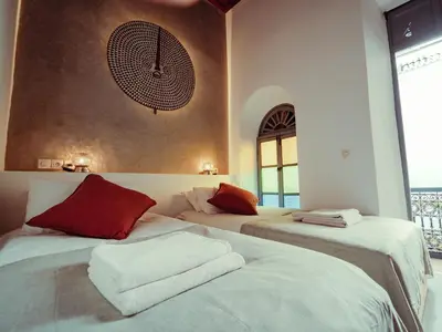 two beds in a room with a clock on the wall at Riad La Smala in Marrakech