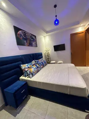 a bedroom with a large bed and a blue couch at Appartements Guéliz Zerktouni in Marrakech