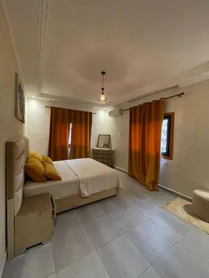 a bedroom with a bed and a window with orange curtains at Appartements Guéliz Zerktouni in Marrakech
