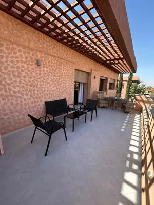 a patio with black chairs and a wooden pergola at Villa djelloul s in Marrakech