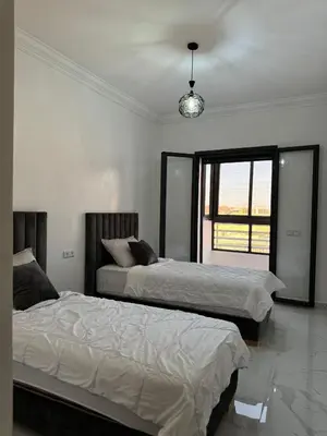 two beds in a white room with a window at Marrakech apartement in Marrakech